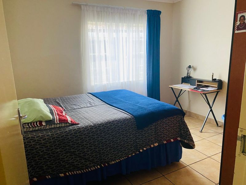 A functional bedroom featuring tiled flooring and a window with a curtain rod, providing a neutral space ready for personalization.
