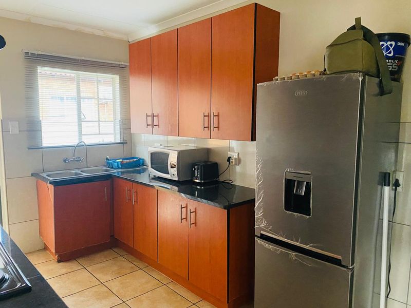 A functional kitchen featuring laminate cabinetry, granite countertops, a double bowl sink, and tiled flooring. The space offers practical storage and workspace.