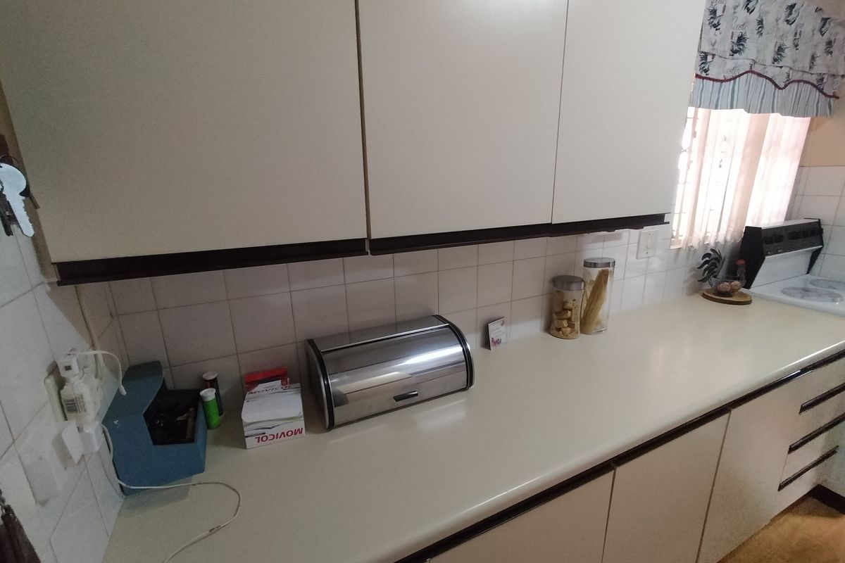 A functional kitchen area featuring laminate countertops, tiled backsplash, and built-in cabinetry, providing a practical workspace within the retirement village unit.