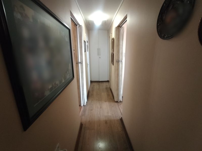 A clean, well-maintained hallway featuring laminate flooring and a built-in storage cupboard at the end.