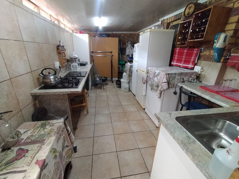 A functional kitchen featuring a gas hob, tiled splashbacks, and ample cabinetry, offering a practical layout that could benefit from modern cosmetic updates.