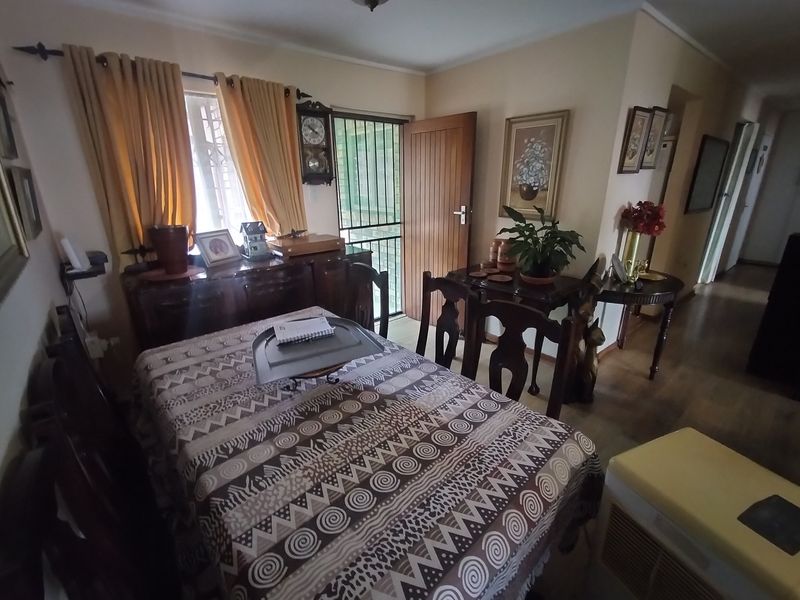 A dining area featuring laminate flooring, a timber door with a security gate, and coving detail.