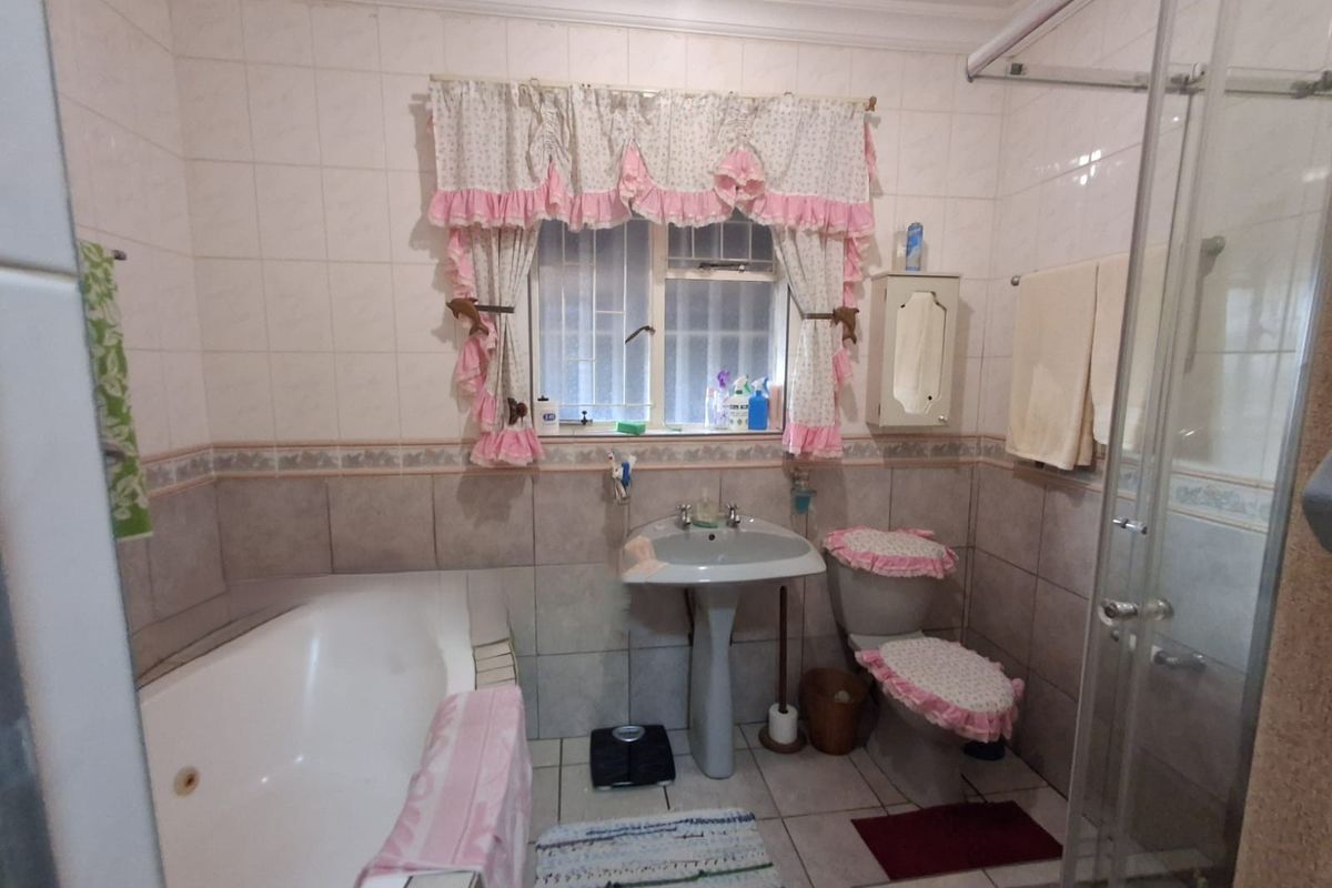 A functional bathroom featuring a pedestal basin, built-in bathtub, and a separate shower enclosure with tiled walls and flooring.
