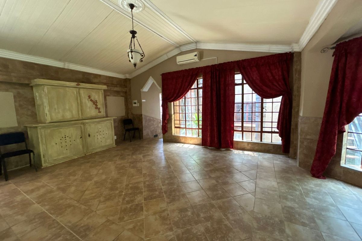 Spacious living area featuring vaulted ceilings, tiled flooring, and large windows that provide ample natural light.