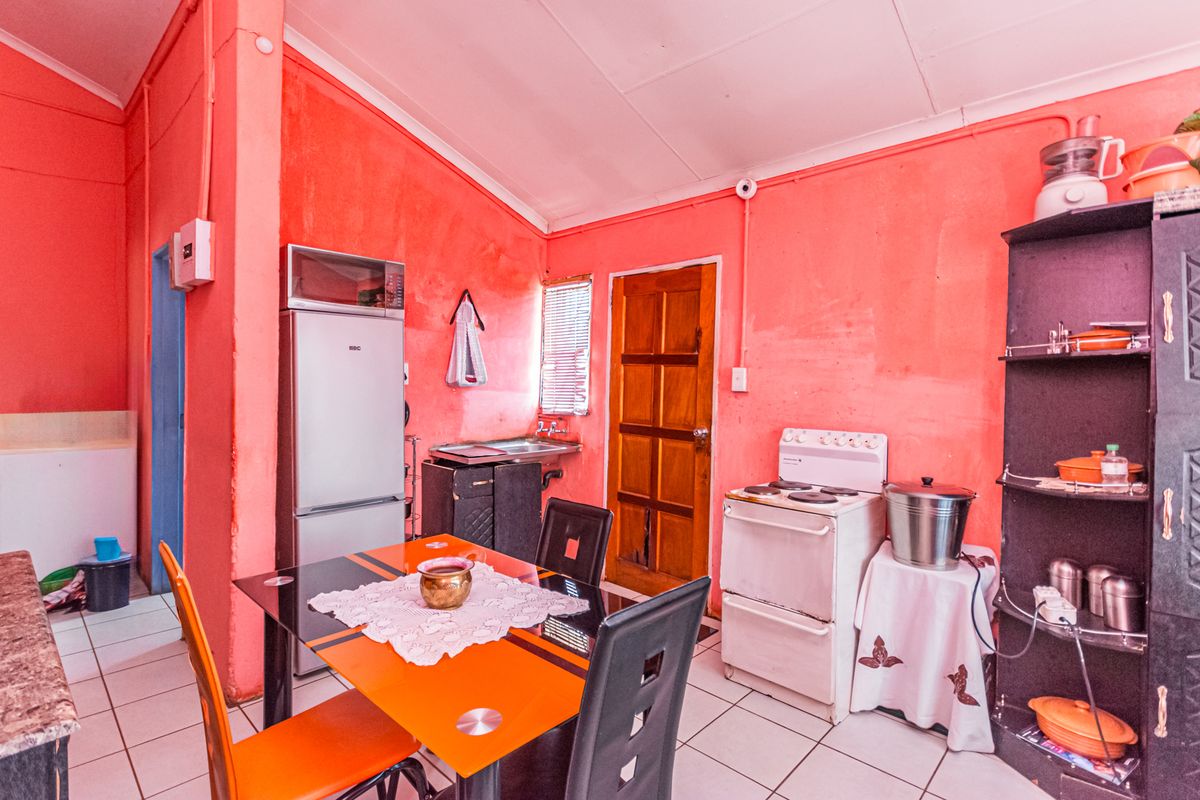 A functional kitchen area featuring tiled flooring, a built-in sink, and space for a freestanding stove and refrigerator.