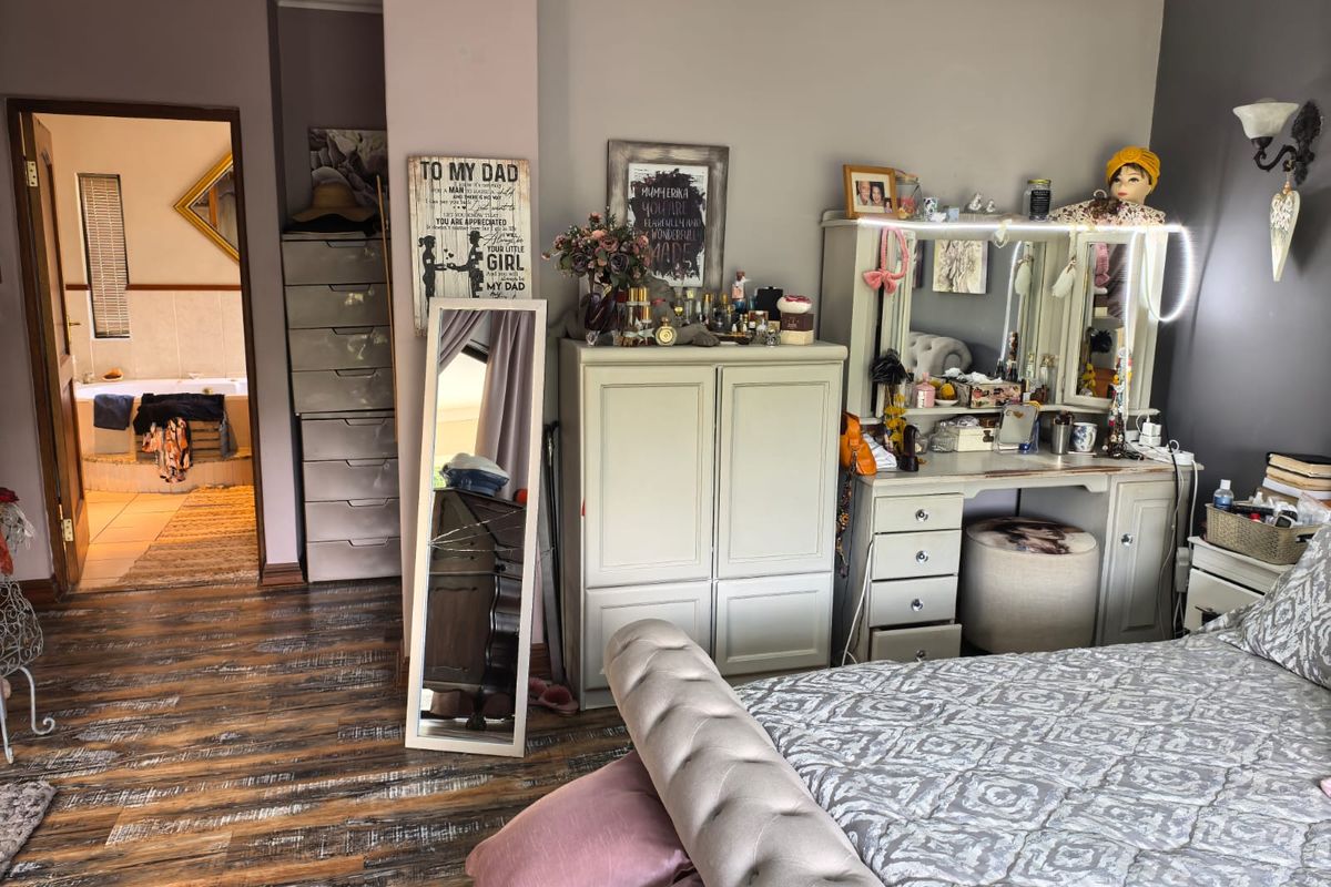 A bedroom featuring laminate flooring and coving, with an adjoining bathroom visible through the doorway.