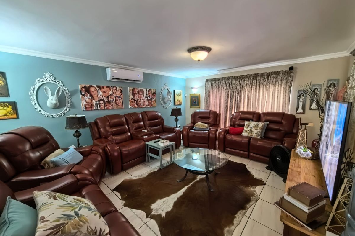 A spacious living room featuring tiled flooring, a wall-mounted air conditioning unit, and decorative coving.