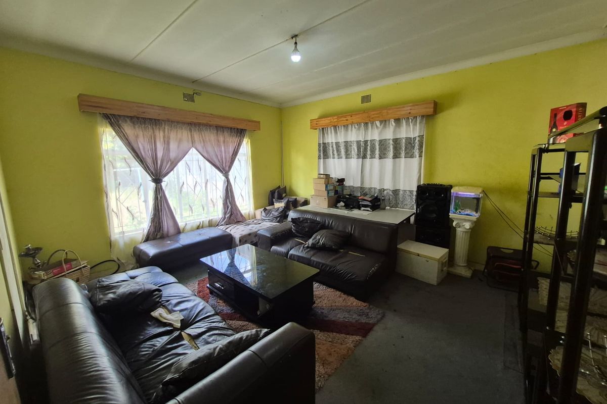 A living room featuring large windows with wooden pelmets, providing natural light to the space.