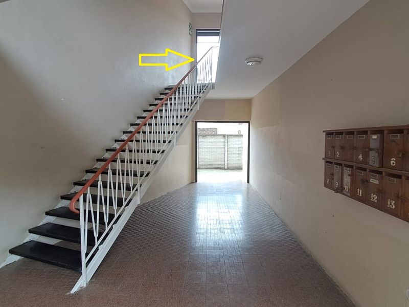 Communal apartment building hallway featuring a staircase with metal balustrade, tiled flooring, and a wall-mounted bank of mailboxes.