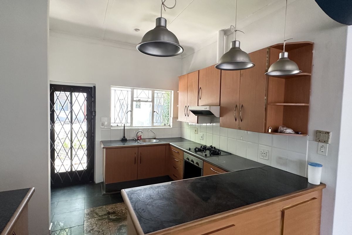 A functional kitchen featuring laminate cabinetry, built-in oven, gas hob, and a breakfast counter, offering a practical layout with direct exterior access.