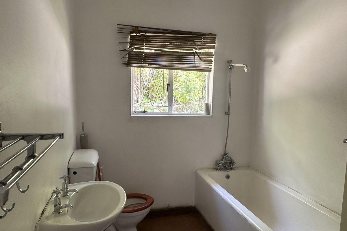 A functional bathroom featuring a bathtub, pedestal basin, and toilet, with a window providing natural light and ventilation.