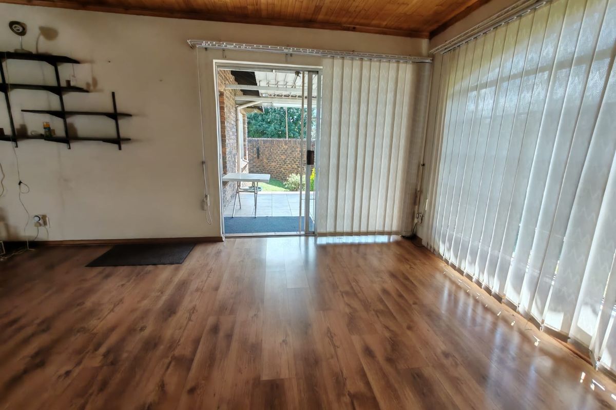 Spacious living area featuring wood-look laminate flooring, timber-clad ceiling, and large sliding glass doors providing direct access to the rear patio.