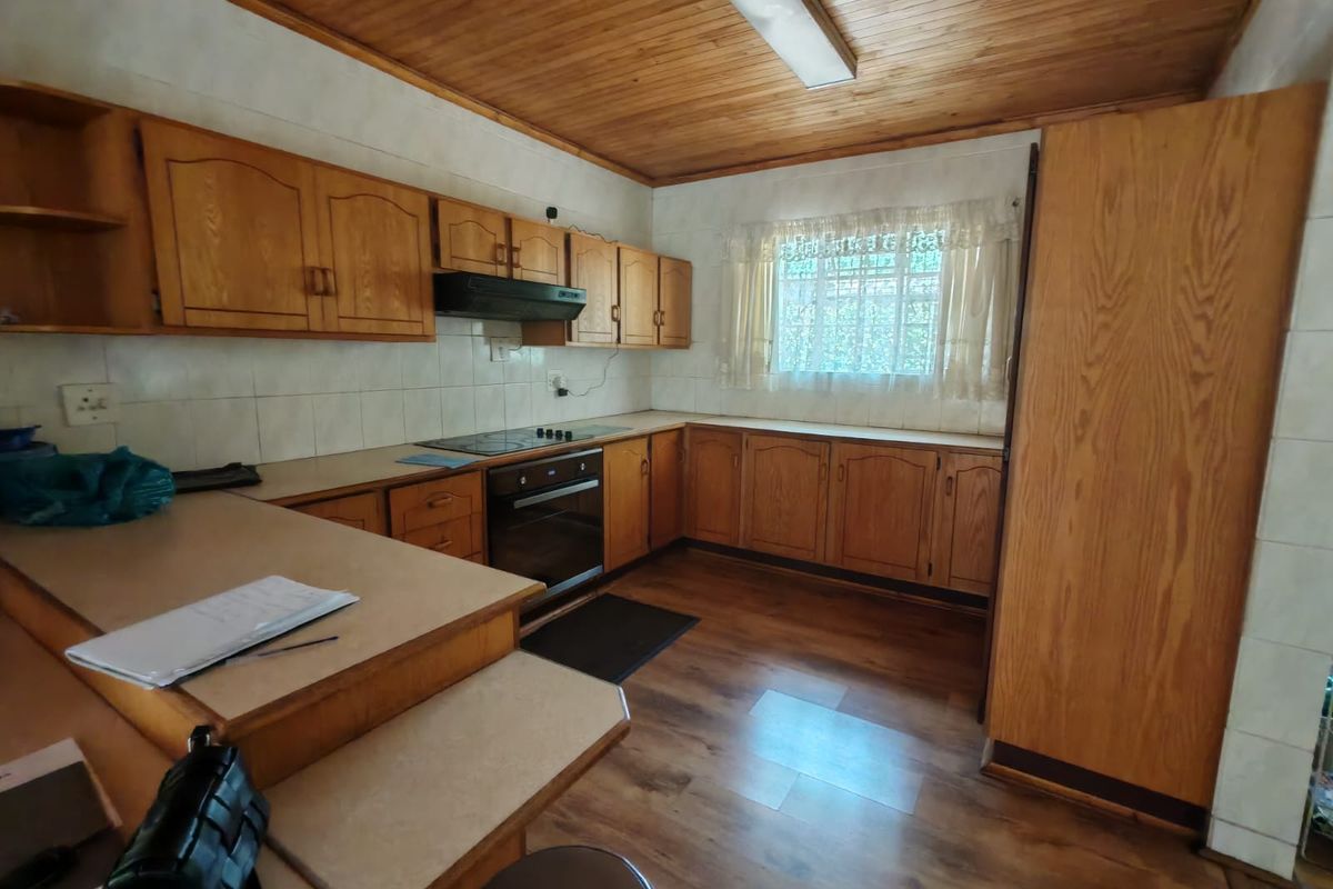 A functional kitchen featuring wood cabinetry, built-in oven and hob, tiled backsplash, and wood-look flooring with a timber-paneled ceiling.