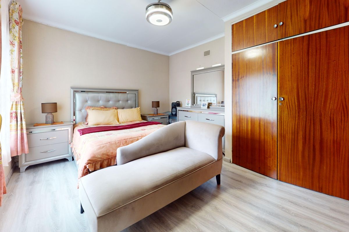 A well-proportioned bedroom featuring light laminate flooring and extensive built-in wooden cabinetry for storage.