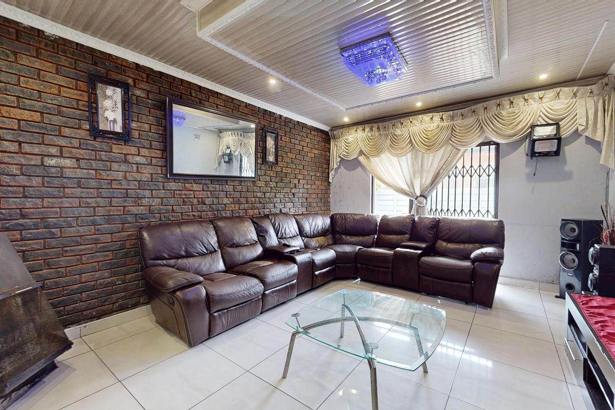 A living room featuring an exposed brick feature wall, tiled flooring, and a built-in fireplace, offering a distinct character with potential for modern updates.