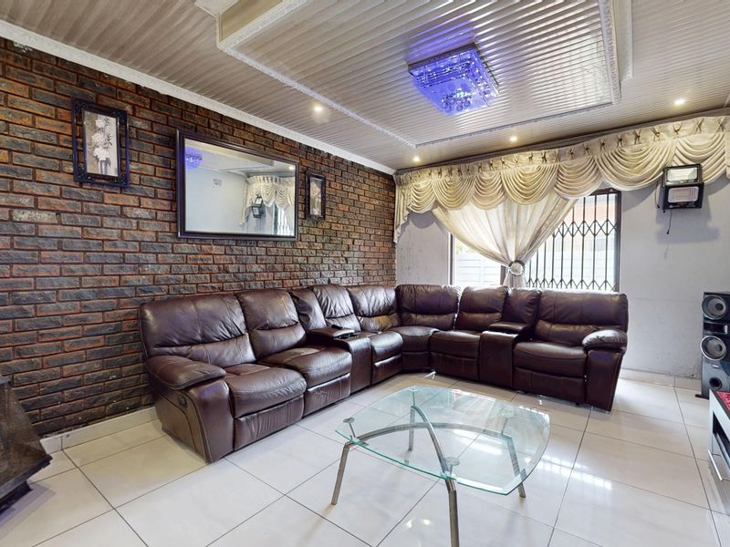 A living room featuring an exposed brick feature wall, tiled flooring, and a built-in fireplace, offering a distinct character with potential for modern updates.