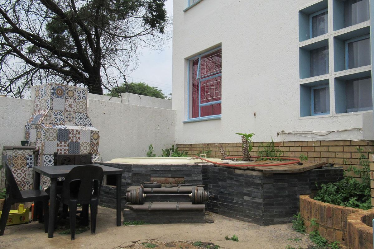 Rear courtyard area featuring a built-in braai, sunken jacuzzi, and brick retaining walls, offering potential for a private outdoor entertainment space.