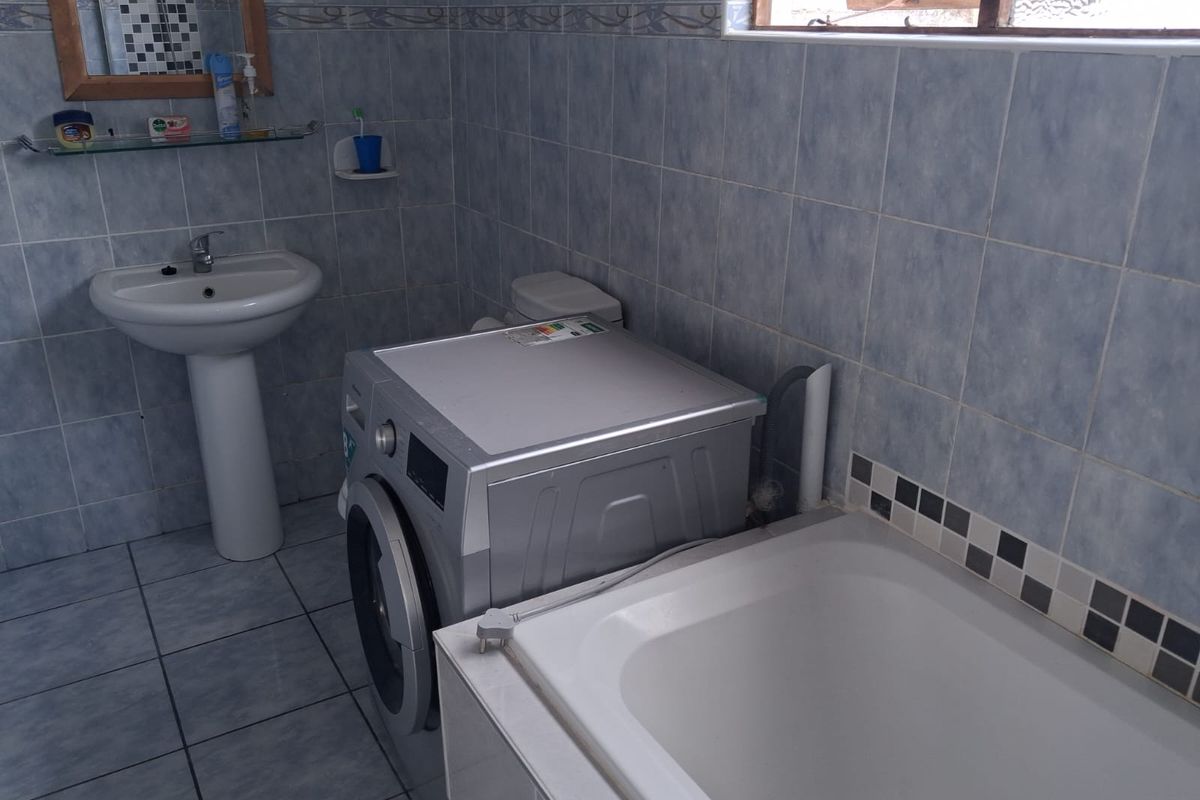 A functional bathroom featuring a pedestal basin, a built-in bathtub, and tiled walls and flooring.