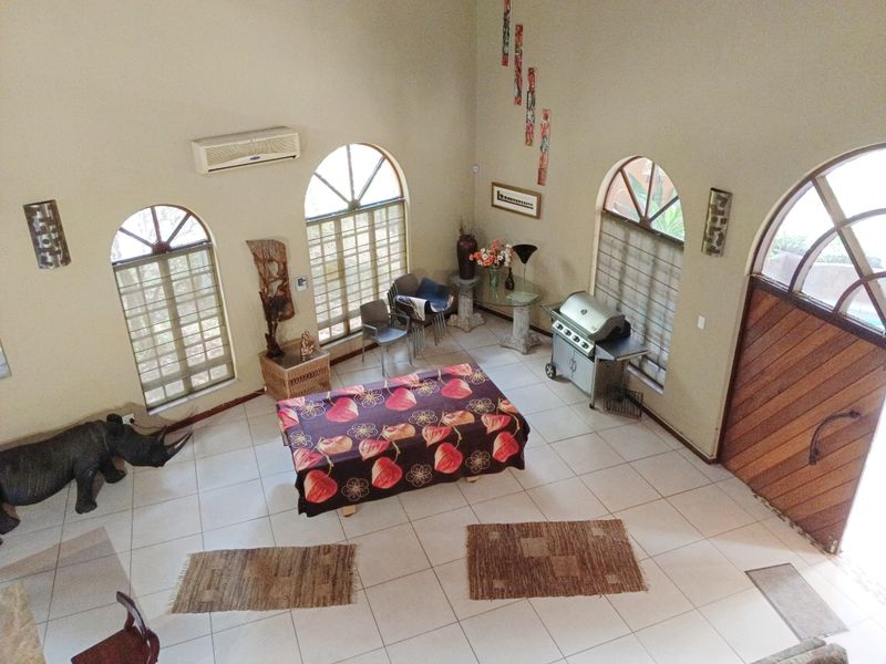 Spacious living area featuring high ceilings, arched windows, tiled flooring, and a split-system air conditioner, offering a bright and open atmosphere.
