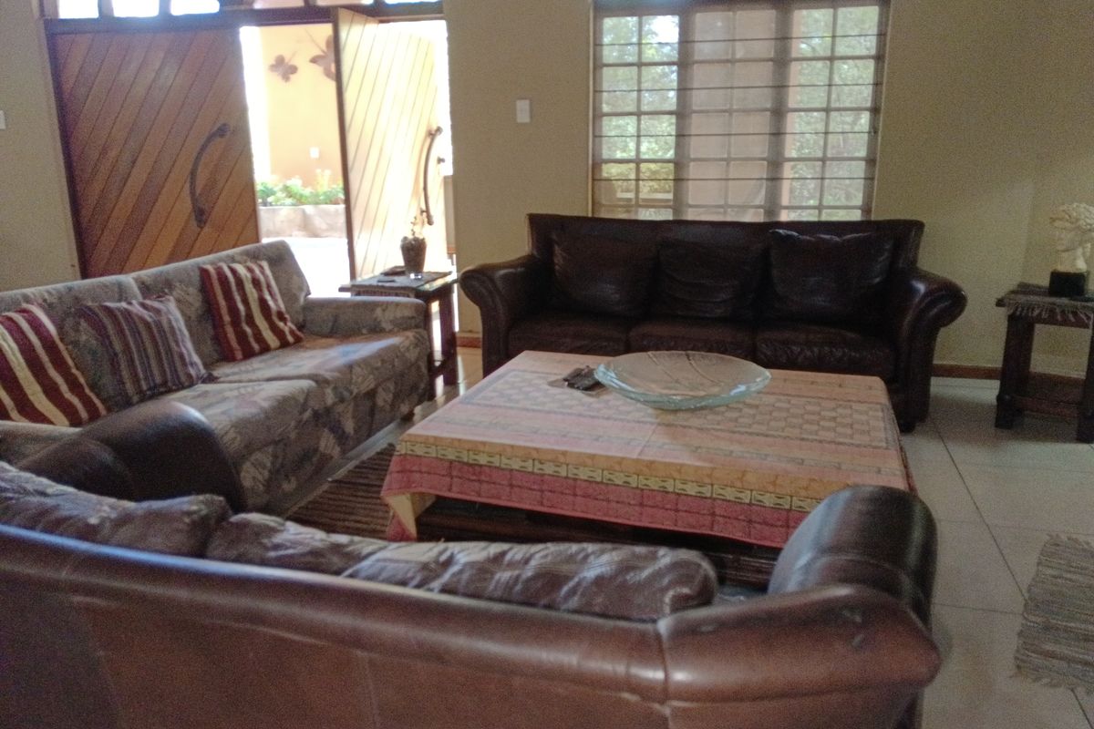 A living room featuring arched windows, tiled flooring, and double doors leading to an outdoor area.
