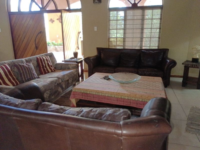 A living room featuring arched windows, tiled flooring, and double doors leading to an outdoor area.