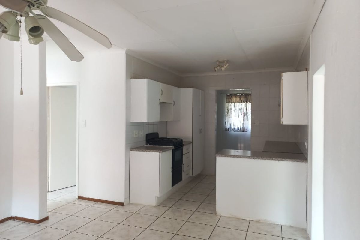 A functional kitchen featuring white built-in cabinetry, laminate countertops, a stove, and tiled flooring, offering a clean and neutral space ready for updates.