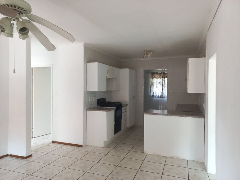 A functional kitchen featuring white built-in cabinetry, laminate countertops, a stove, and tiled flooring, offering a clean and neutral space ready for updates.