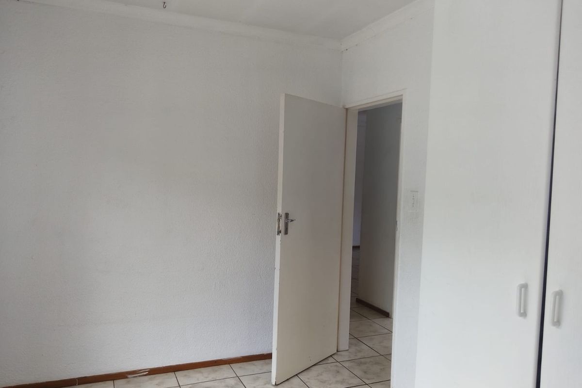 An empty bedroom featuring tiled flooring and built-in cupboards, offering a blank canvas for personalization.