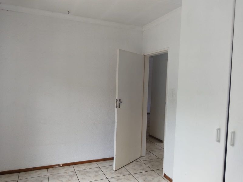 An empty bedroom featuring tiled flooring and built-in cupboards, offering a blank canvas for personalization.
