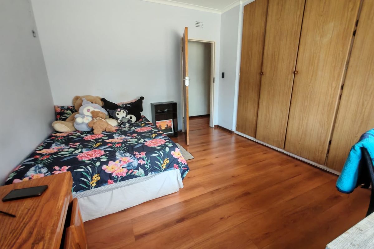 A bedroom featuring laminate flooring and a large built-in wooden wardrobe, providing ample storage space.