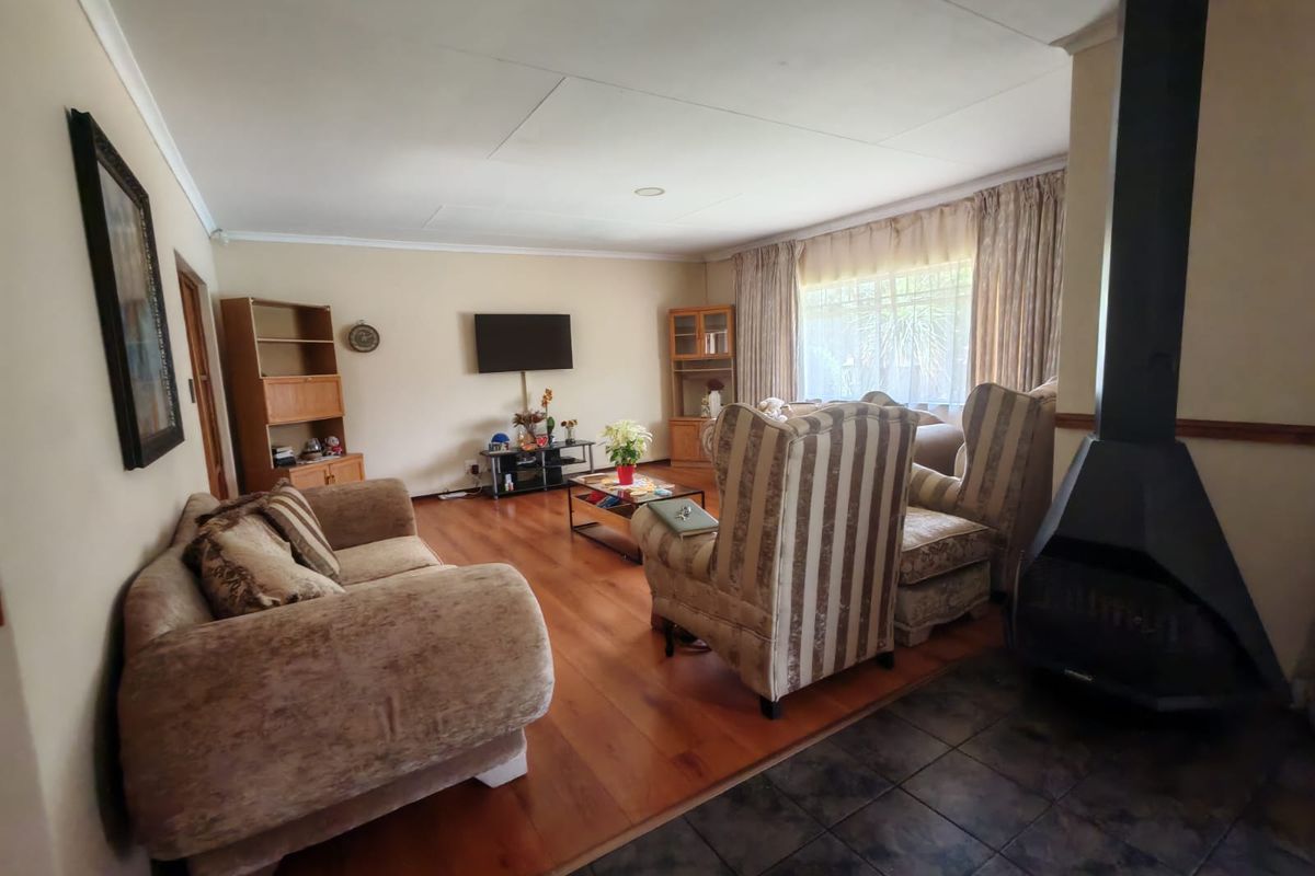 Spacious living room featuring a prominent freestanding fireplace, a mix of timber and tiled flooring, and large windows with curtains.