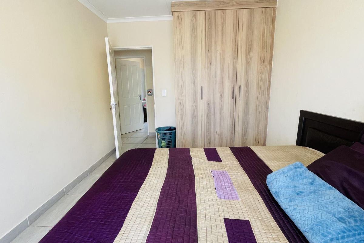 A bedroom featuring light-toned built-in wardrobes, tiled flooring, and neutral wall finishes, providing a functional and clean living space.