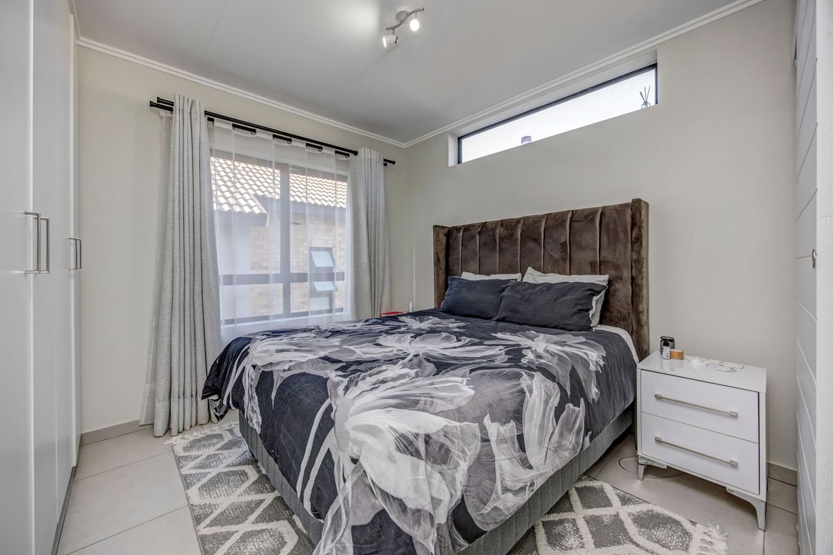 A well-maintained bedroom featuring built-in cupboards, tiled flooring, and a high-level clerestory window for natural light.