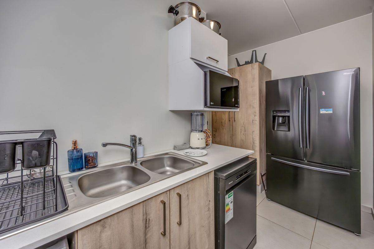 A functional kitchen area featuring wood-look cabinetry, a double stainless steel sink, and integrated appliance space.