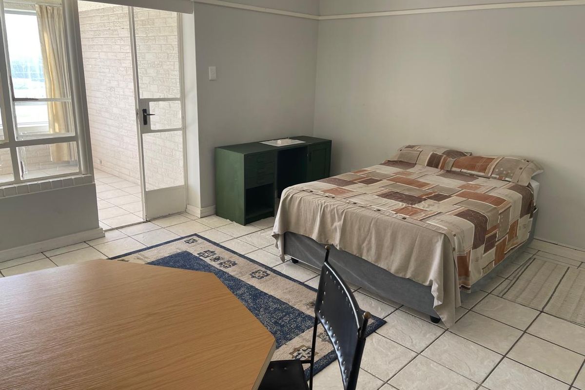 A bedroom featuring tiled flooring and a sliding glass door providing access to an outdoor patio area.