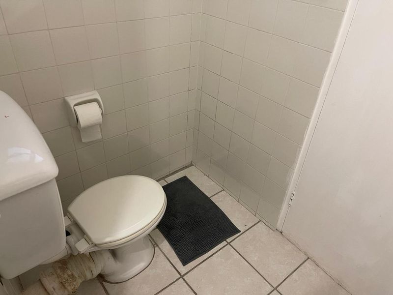 A compact bathroom featuring ceramic wall and floor tiles with a standard toilet fixture.