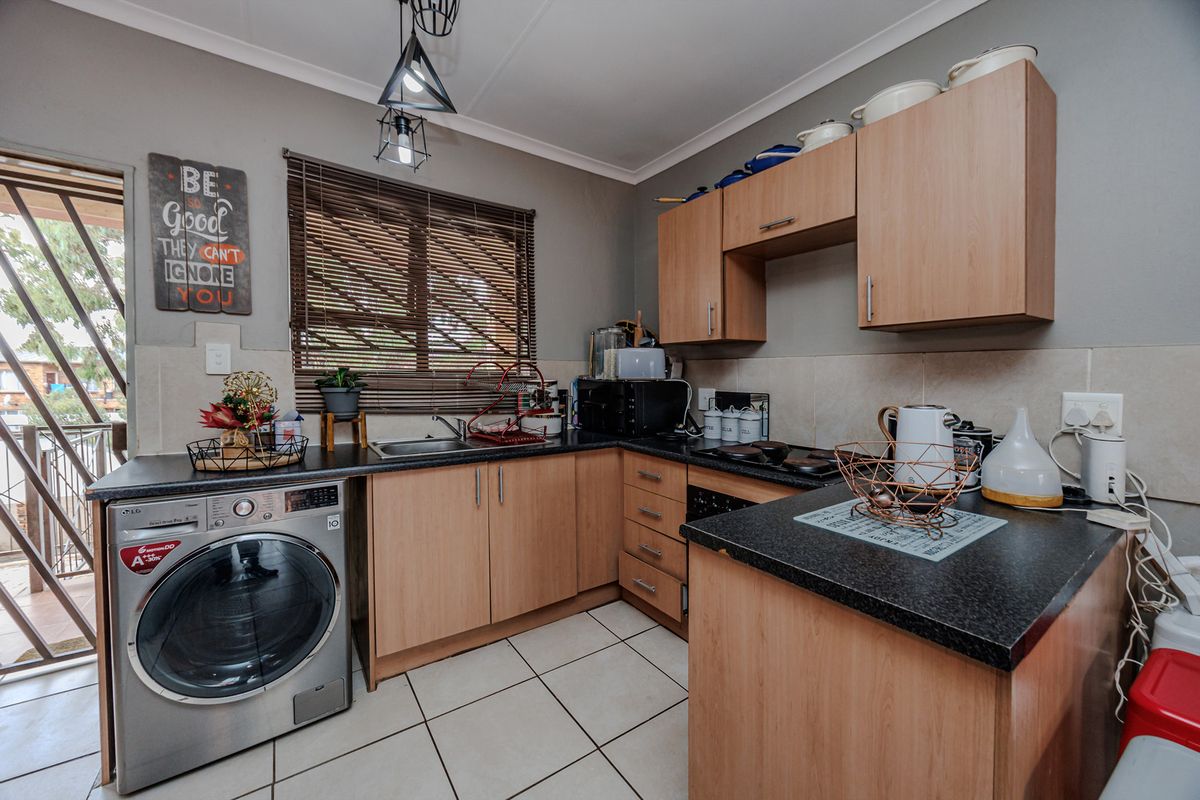 Compact kitchen featuring laminate cabinetry, dark countertops, tiled flooring, and direct access to an outdoor area, providing a functional workspace.