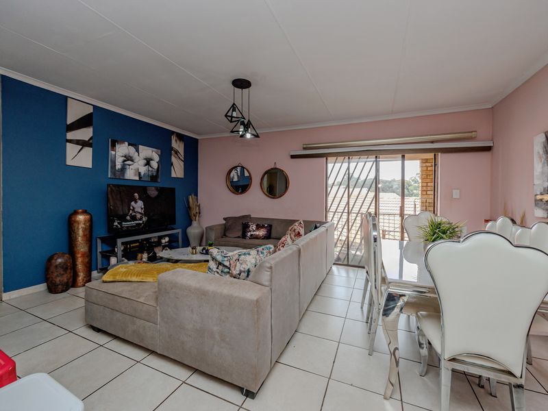 Open-plan living and dining area featuring ceramic floor tiles, pendant lighting, and a sliding glass door providing access to the exterior.