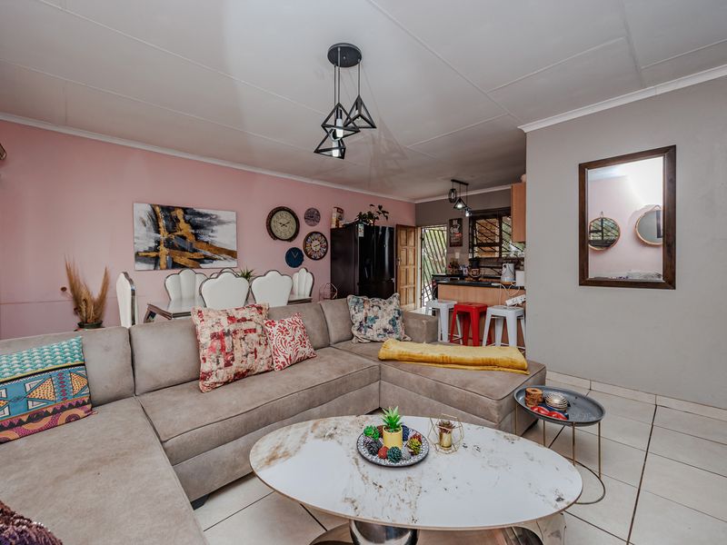 Open-plan living and dining area featuring tiled flooring, a breakfast bar, and modern pendant lighting, creating a functional and connected living space.