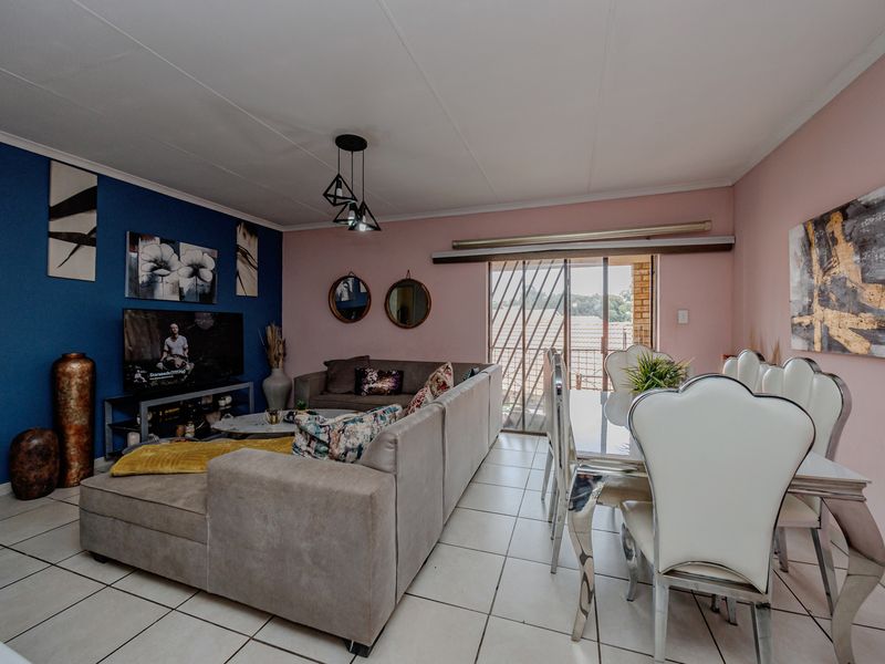 Open-plan living and dining area featuring tiled flooring, modern pendant lighting, and a sliding glass door with security gate leading to the exterior.