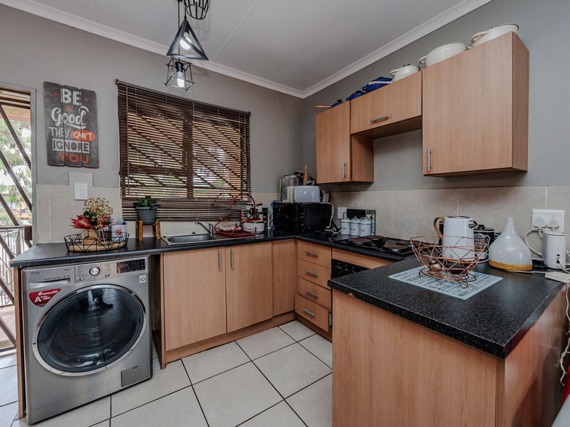 Compact kitchen featuring laminate cabinetry, dark countertops, tiled flooring, and direct access to an outdoor area, providing a functional workspace.