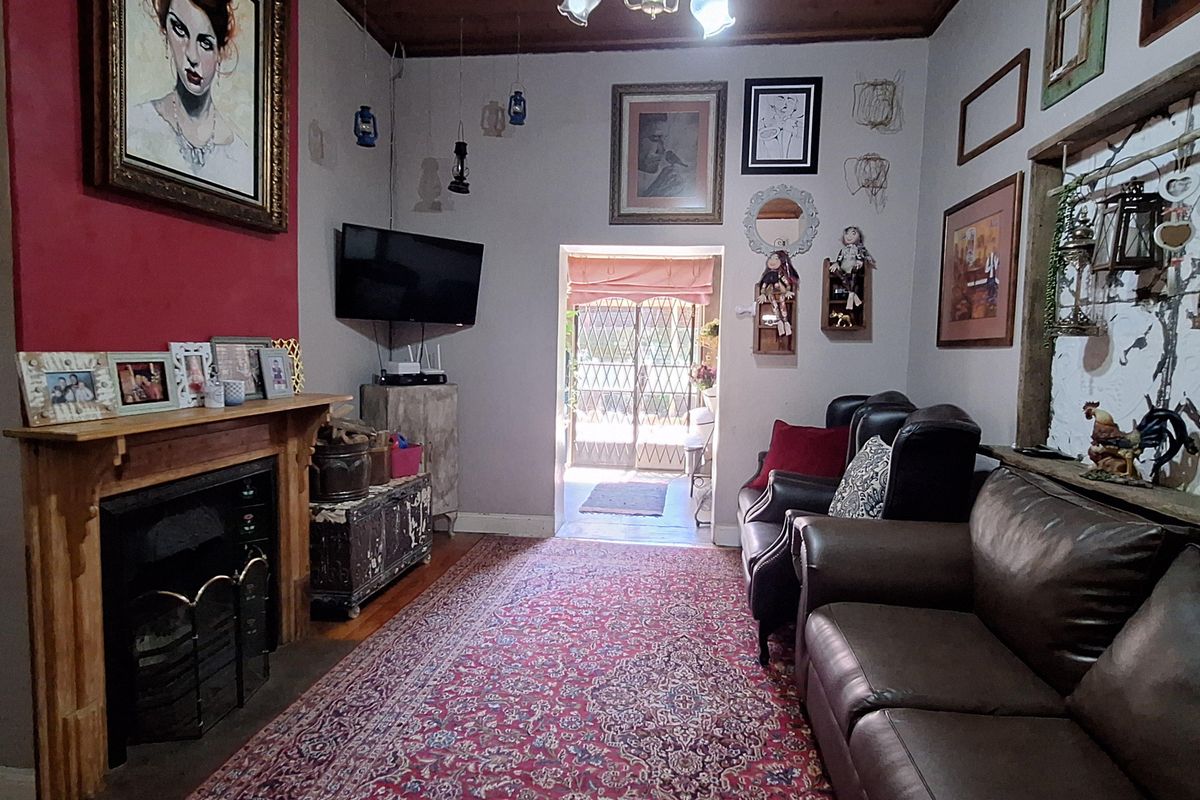 Living room featuring a traditional fireplace with a wooden mantel, timber-clad ceiling, and direct access to an outdoor area through a security gate.