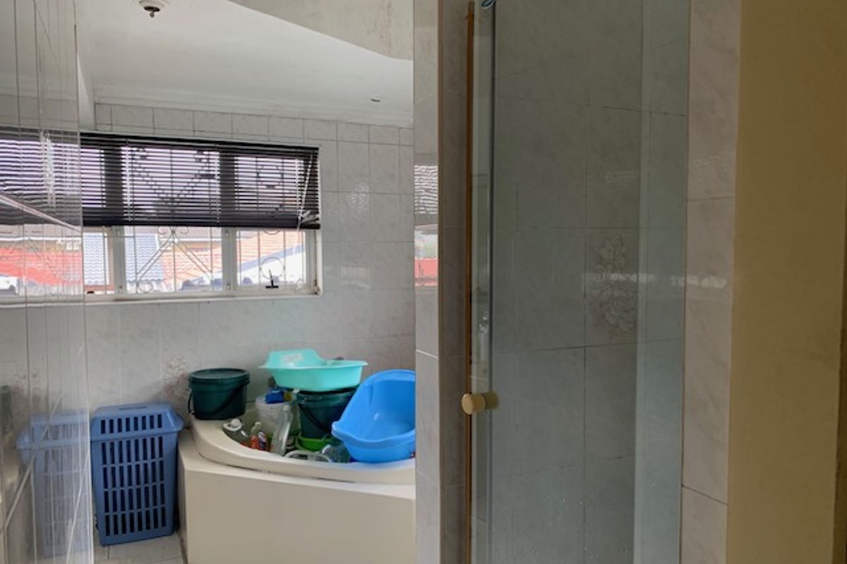 A bathroom featuring a built-in corner bathtub, a separate shower enclosure, and tiled finishes throughout, requiring cosmetic updates to modernize the space.