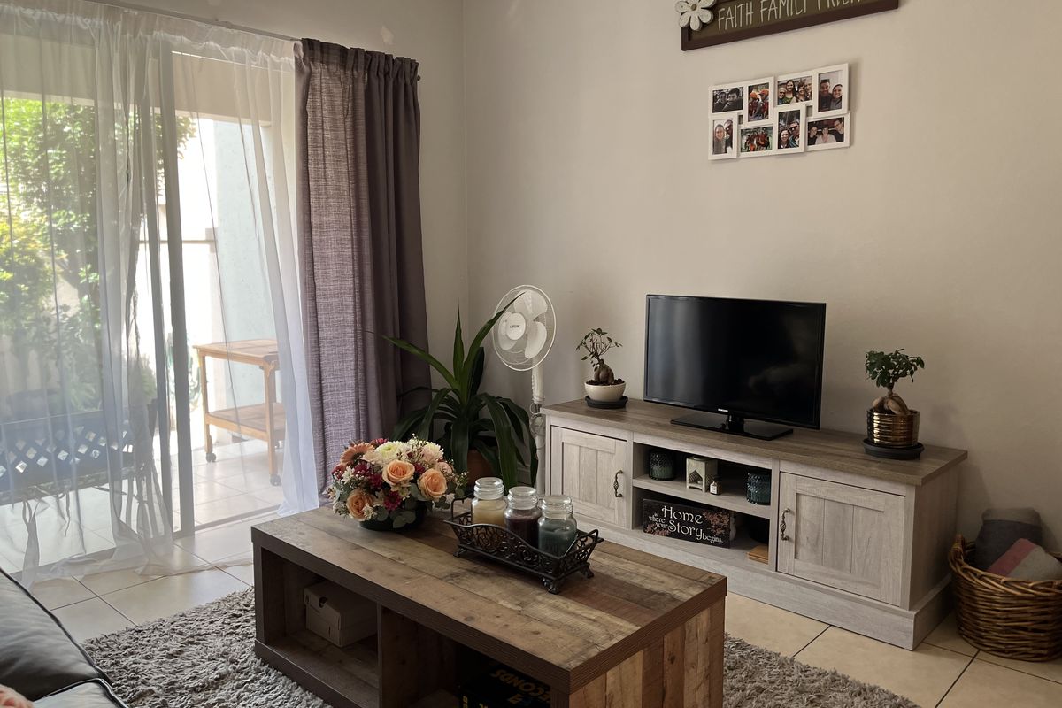 A comfortable living room featuring tiled flooring and large sliding glass doors that provide direct access to an outdoor patio area.