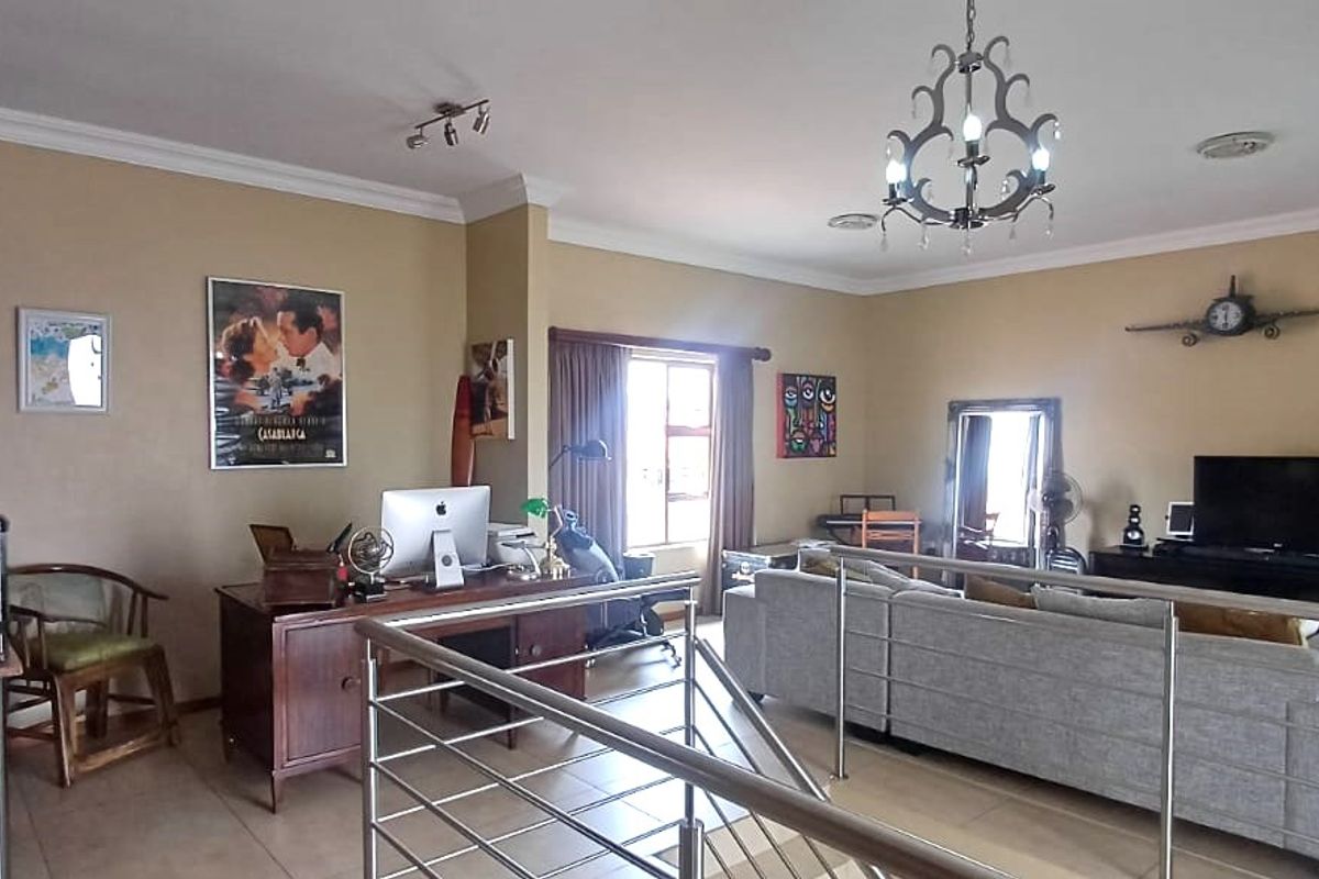 Spacious open-plan living area featuring tiled flooring, modern stainless steel balustrades, and decorative lighting fixtures.