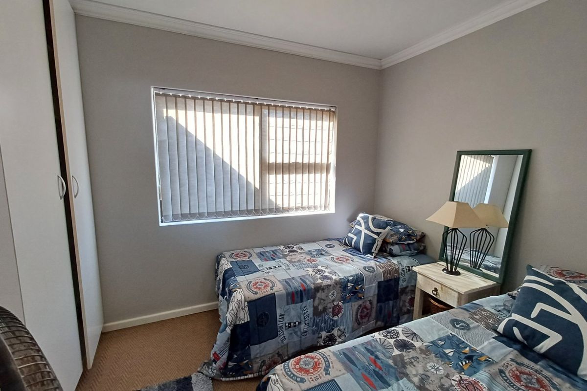 A functional bedroom featuring built-in cupboards, neutral wall finishes, and vertical window blinds, providing a comfortable and practical living space.