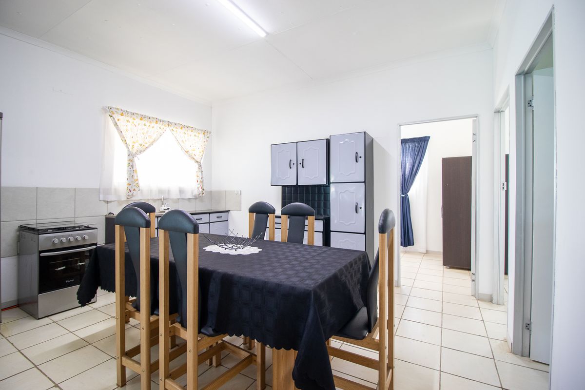 A functional kitchen and dining area featuring tiled flooring, built-in cabinetry, and a freestanding stove, offering a practical layout for daily use.