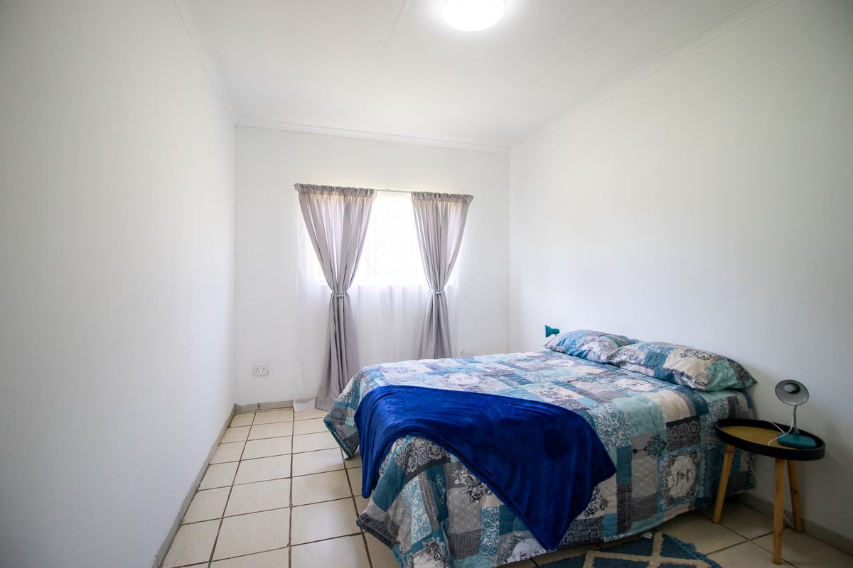 A simple bedroom featuring tiled flooring and neutral white walls, providing a clean and functional space.