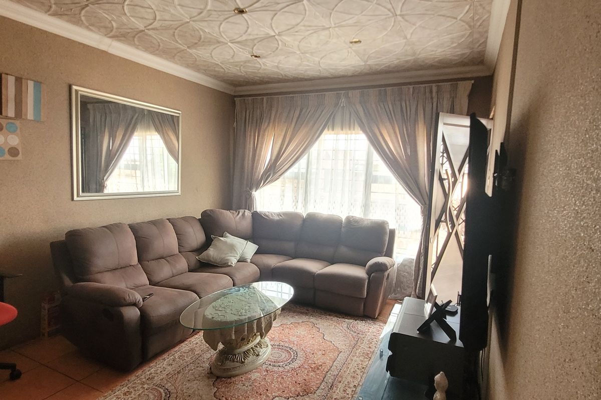 A living room featuring textured ceiling detailing and tiled flooring, providing a functional space for relaxation.
