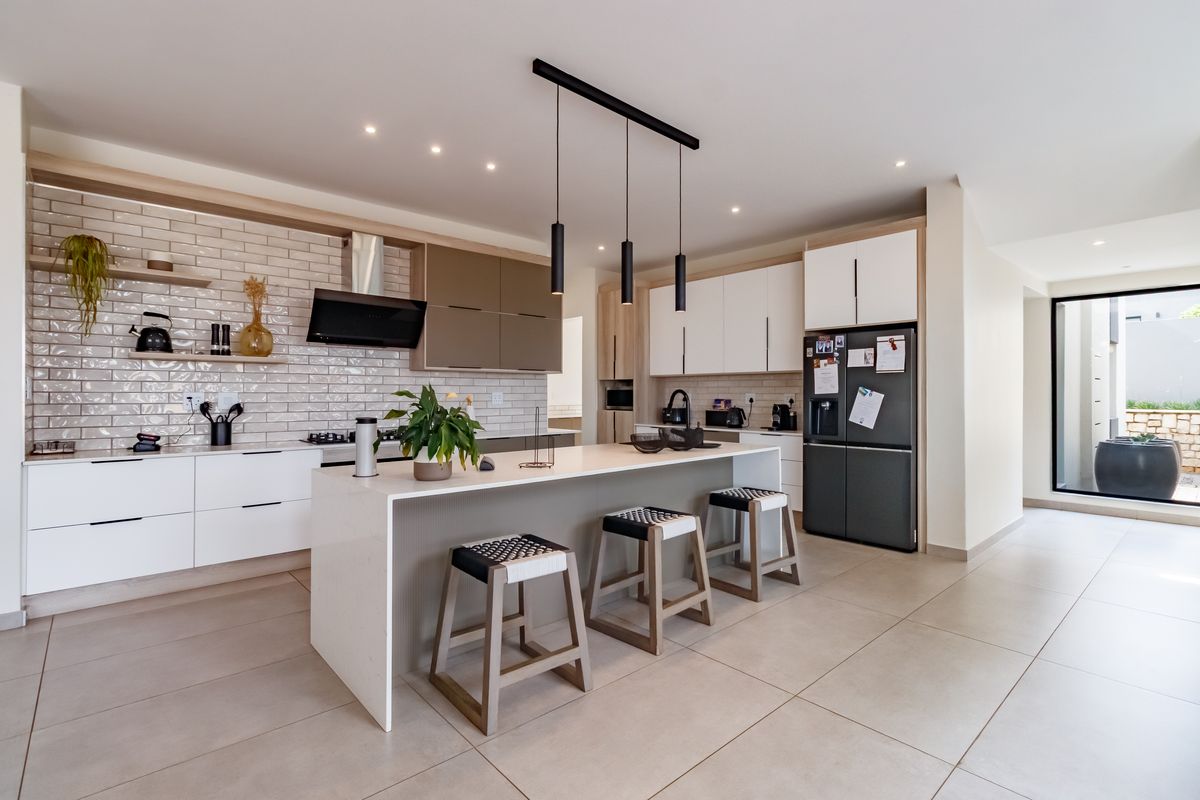 Modern kitchen featuring a central island, sleek cabinetry, subway tile backsplash, and high-quality finishes with integrated lighting and contemporary design elements.